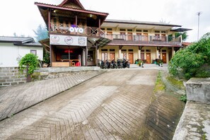 A two-story building with a coffee shop on the ground floor, a balcony with a railing, and several motorcycles parked outside. - Super OYO 2961 Artana Bed & Breakfast (Pangalengan)