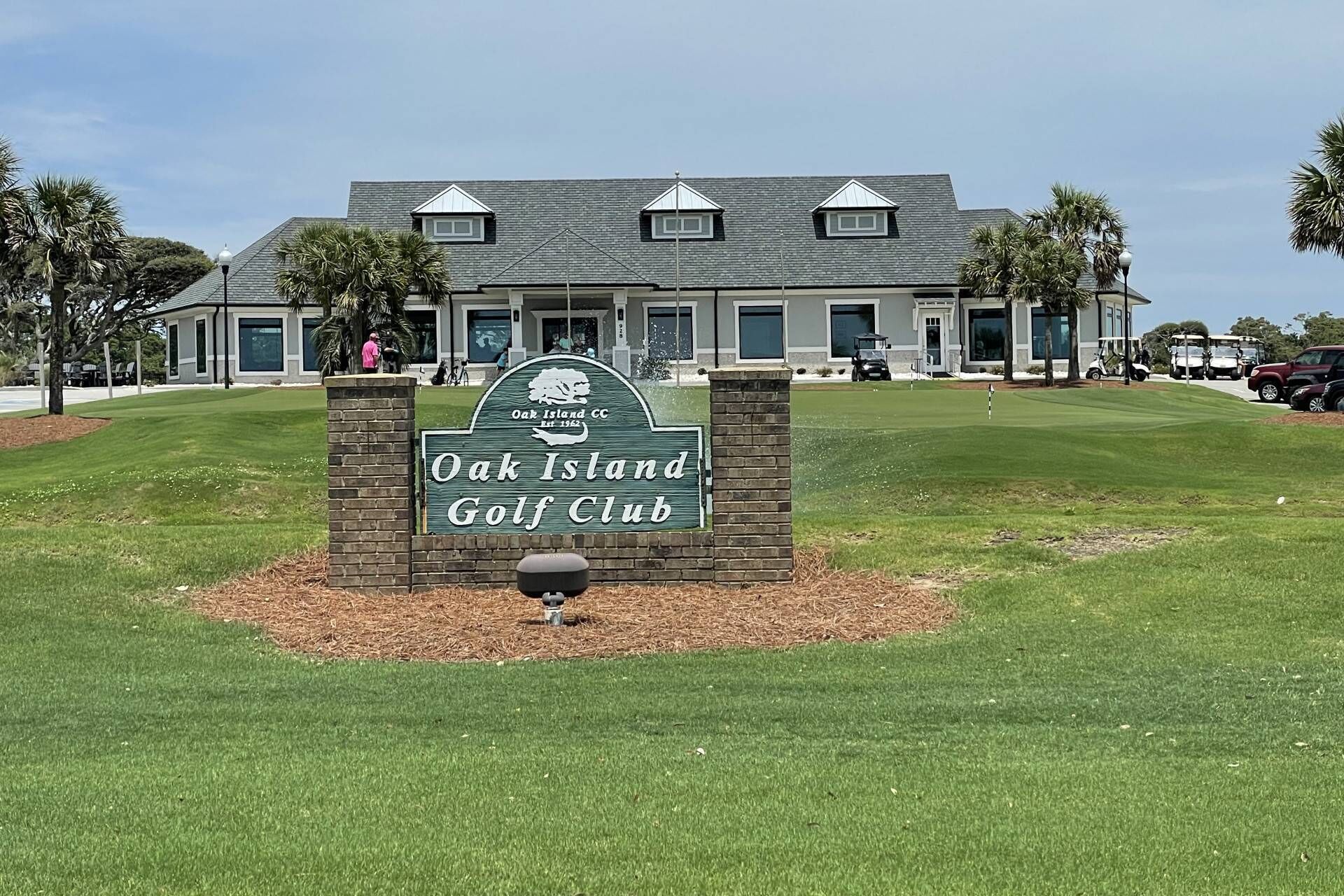 A sign for Oak Island Golf Club with a modern building in the background.