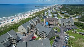 Un hôtel situé sur la côte, composé de plusieurs bâtiments, doté d’un parking et donnant sur une plage équipée de parasols.
