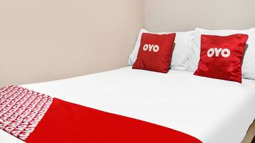 A bed with a white and red bedspread, two pillows with the word "OYO" on them, and a red and white blanket.