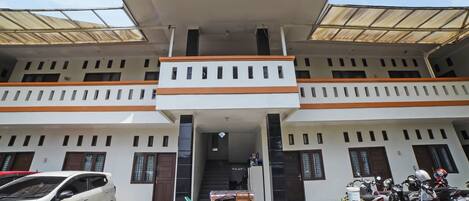 A two-story building with a central entrance, a covered balcony, and a staircase leading to the upper floor.