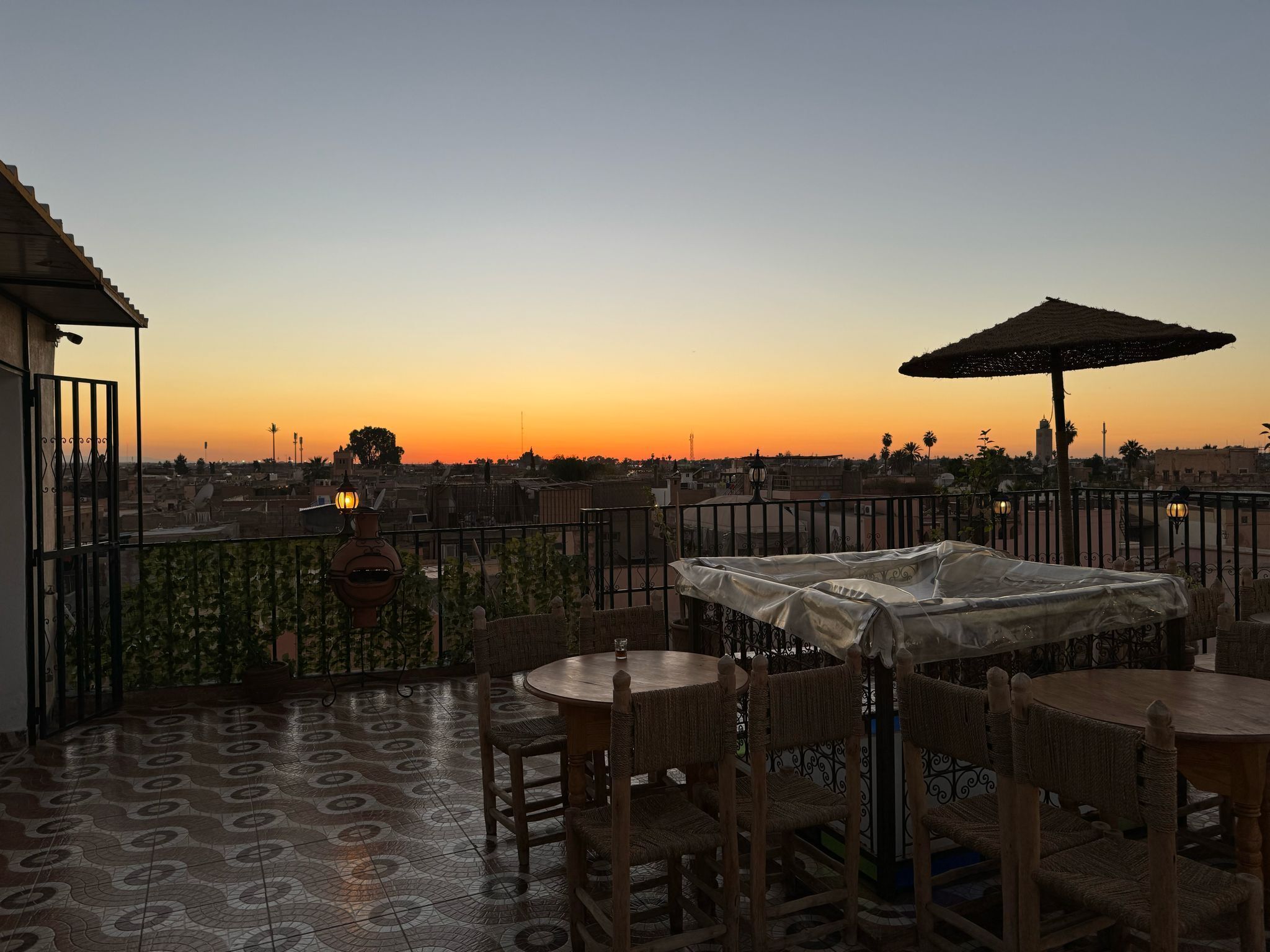 A terrace with a patterned floor, a table with chairs, and an umbrella.