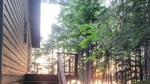 A wooden staircase leading to a deck with a view of a forest.