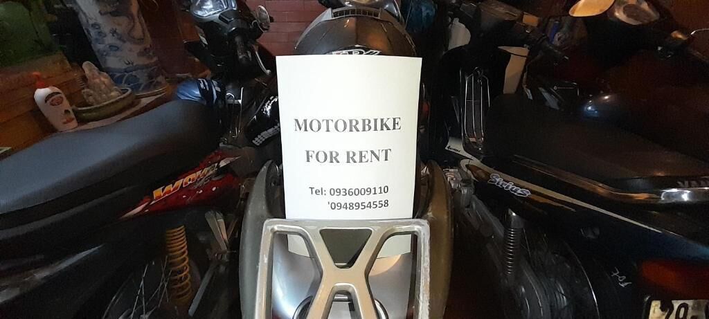 A motorbike for rent with a sign displaying contact information.