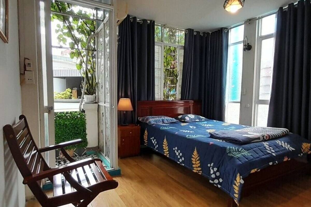 A bedroom with a bed, a chair, a nightstand, and a window with curtains.
