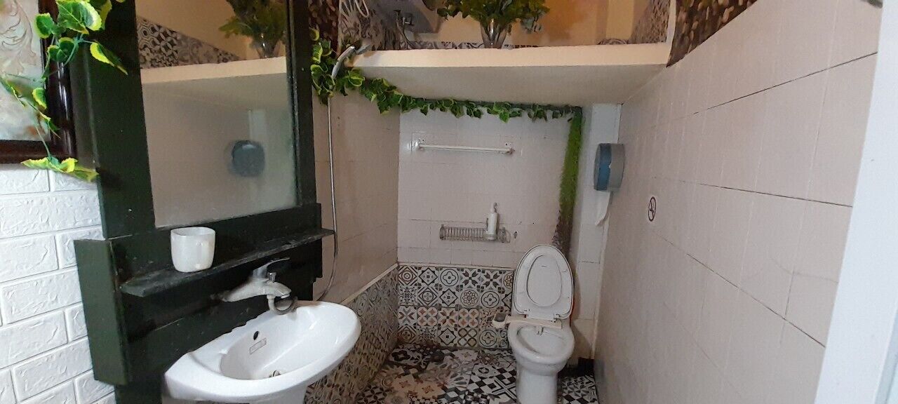 Une salle de bain avec un lavabo, des toilettes et une douche, le tout de couleur blanche.