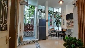 A kitchen with a refrigerator, dining table, chairs, and potted plants. - Green Homestay Ha Noi (Hanoi)