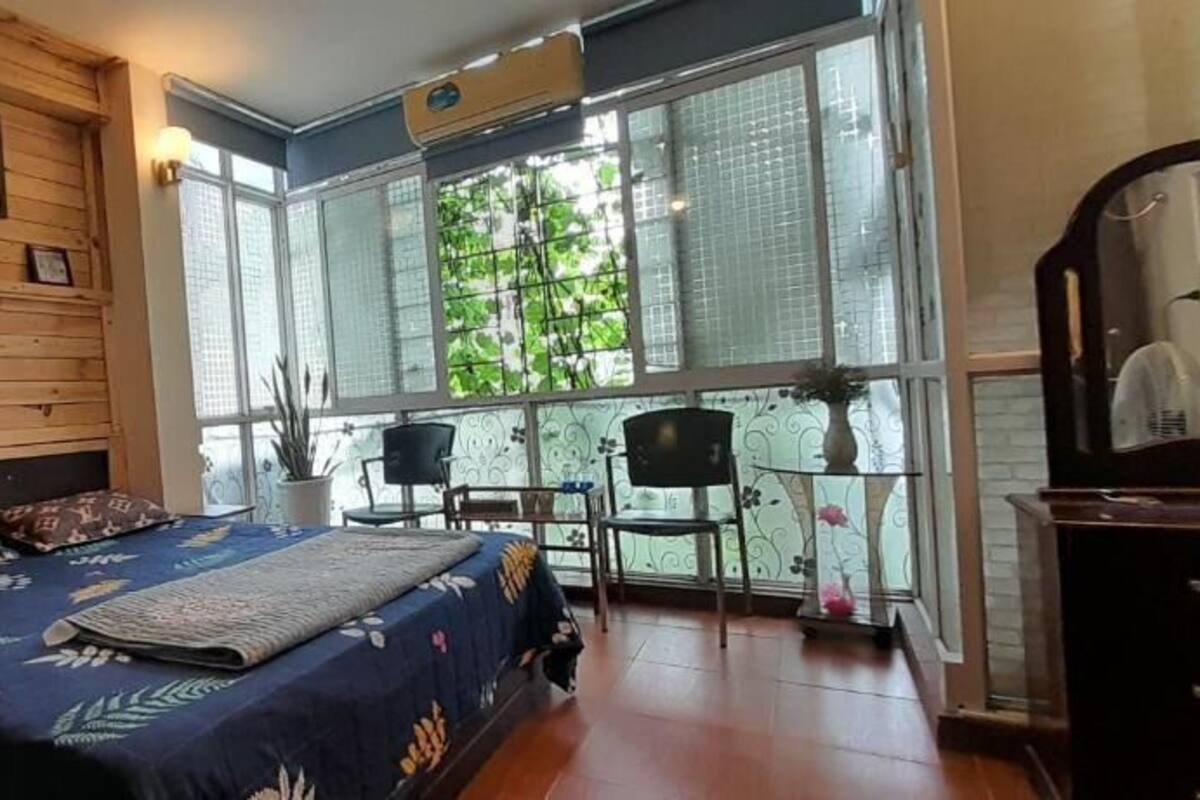 A bedroom with a bed, a desk, and a large window with a view of greenery.
