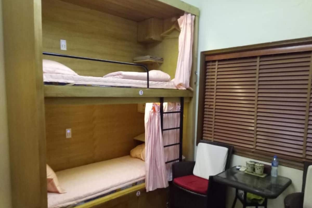 A bunk bed room with a small table and a chair.