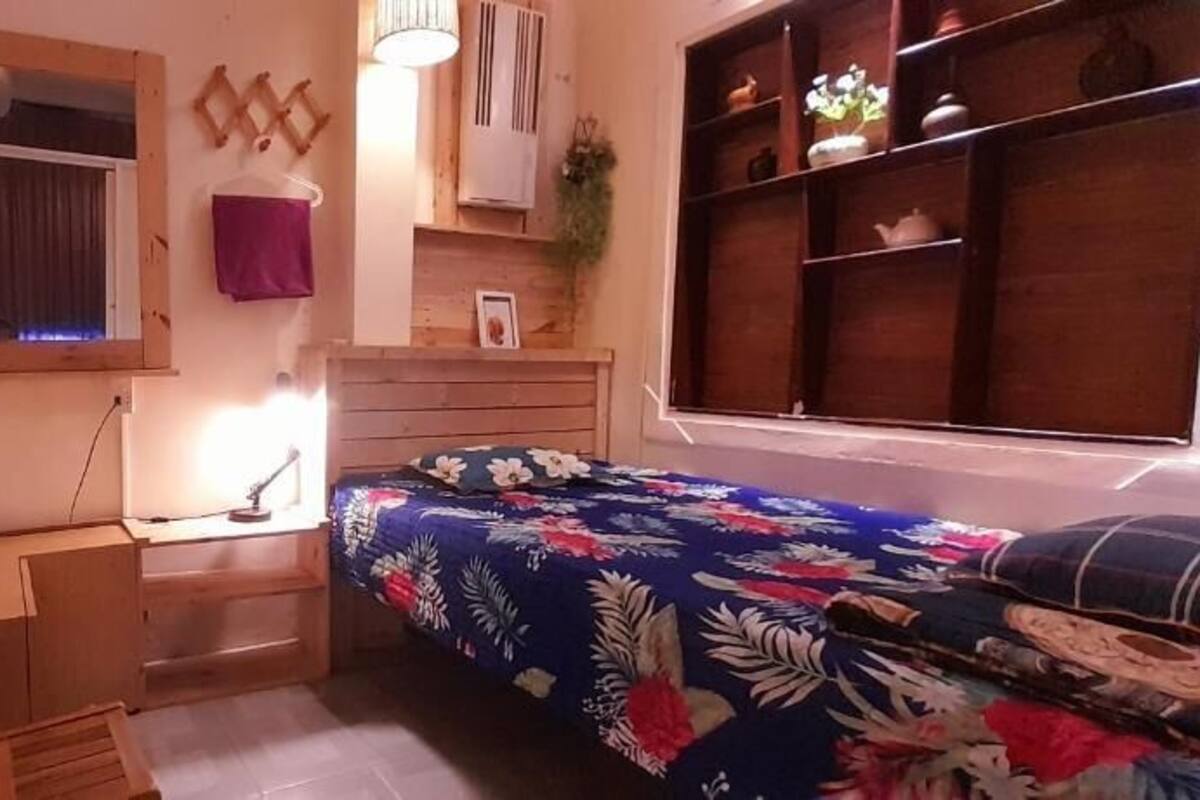 A bedroom with a bed, a desk, and a dresser.