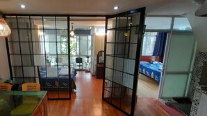 A room with a dining table, chairs, a glass partition, and a view of a balcony. - Green Homestay Ha Noi (Hanoi)