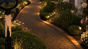 Ein Gartenweg führt zu einer Laube, umgeben von gepflegten Hecken und blühenden Pflanzen.