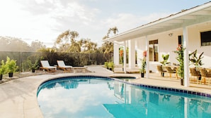 Ein Pool mit Liegestühlen und einer überdachten Terrasse.