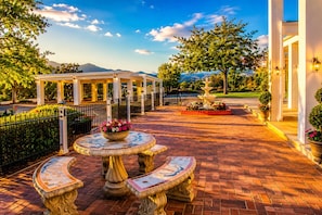 A courtyard with a fountain, a gazebo, and a paved walkway.
