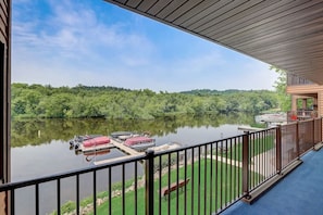 Ein Balkon mit Blick auf einen stillen See, angestellte Boote und bewaldetes Ufer.