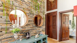 A stone wall with hanging plants, a round mirror, and a blue console table with decorative items. - Refurbished BeachFront Penthouse - Music themed! (Cabarete)