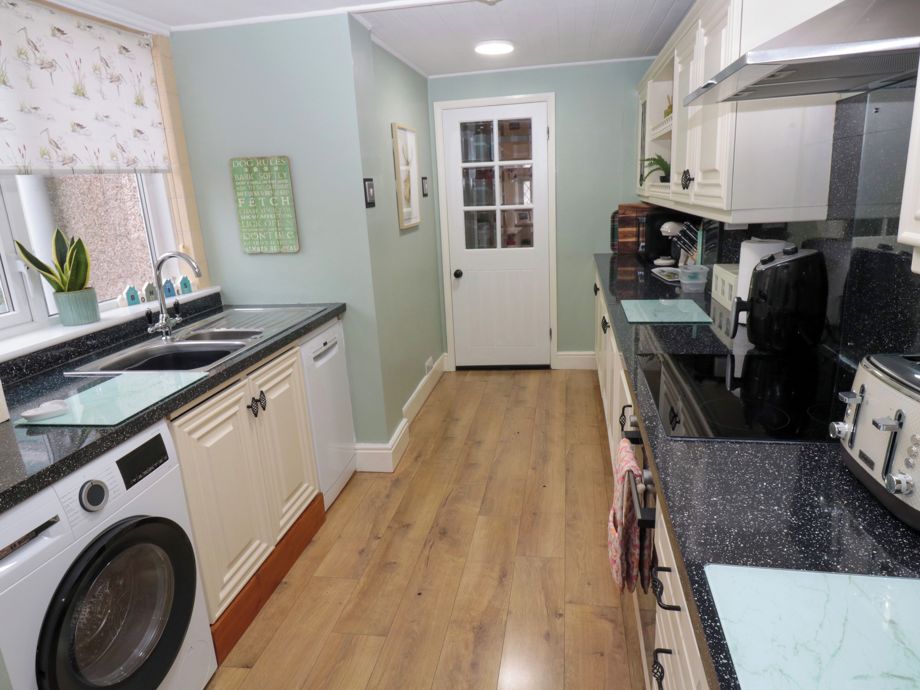 A kitchen with a washing machine, a sink, and a coffee maker.