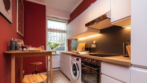Une cuisine compacte équipée d’un lave-linge, d’un four et d’un coin repas avec une table et des chaises.