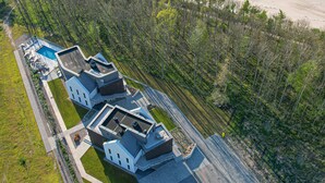 Vue aérienne d’une propriété située sur la côte, avec une piscine, plusieurs bâtiments et une plage.