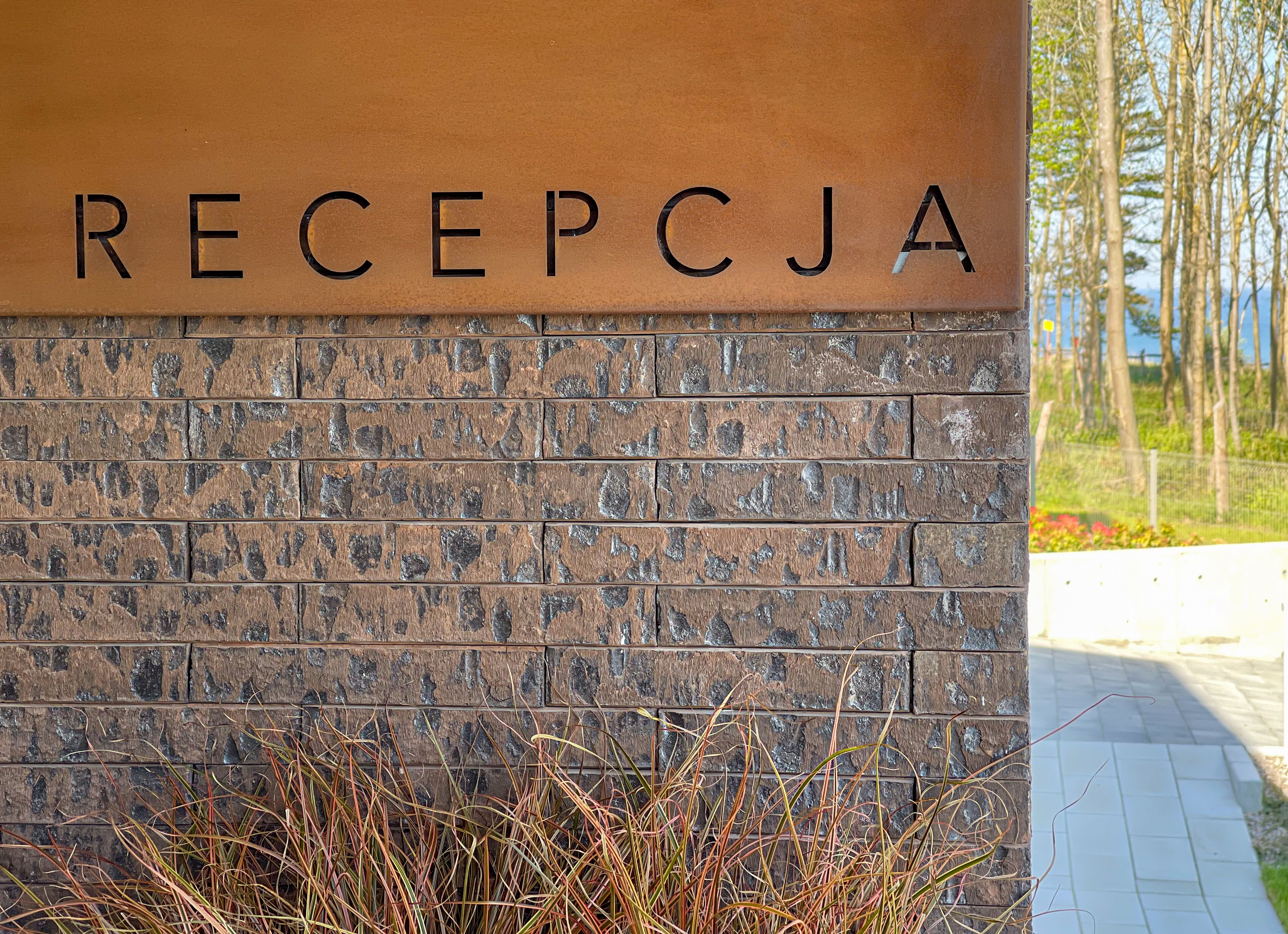 Eine Empfangswand mit der Aufschrift 'RECEPTCJA' und einer Ziegelstruktur.
