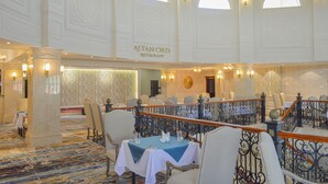 A spacious hotel lobby with a high ceiling, ornate columns, and a sign for 'ALTAN ORD Restaurant'. - Bayangol Hotel & Resort (Ulaanbaatar)