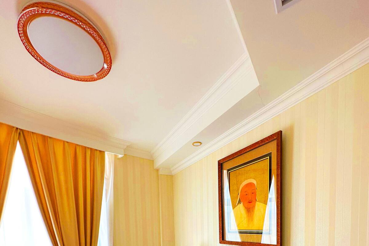 Ein Hotelzimmer mit einem Holztisch, einem gerahmten Bild an der Wand und einem Fenster mit Vorhängen.
