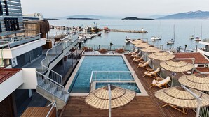 A pool area with lounge chairs and umbrellas, overlooking a marina with boats. - Ma-Si Urla Hotel (Urla)