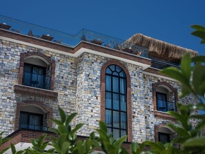 Experience the unique blend of brick and stone masonry at URLA TERAS CAFE, featuring arched windows and a spacious balcony.