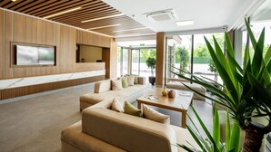 A modern lobby with a large sofa, a flat-screen TV, wooden paneling, and large windows. - Ma-Si Urla Hotel (Urla)