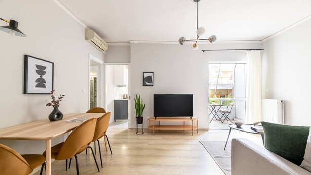 Un salon moderne comprenant un coin repas, un téléviseur à écran plat et un canapé.