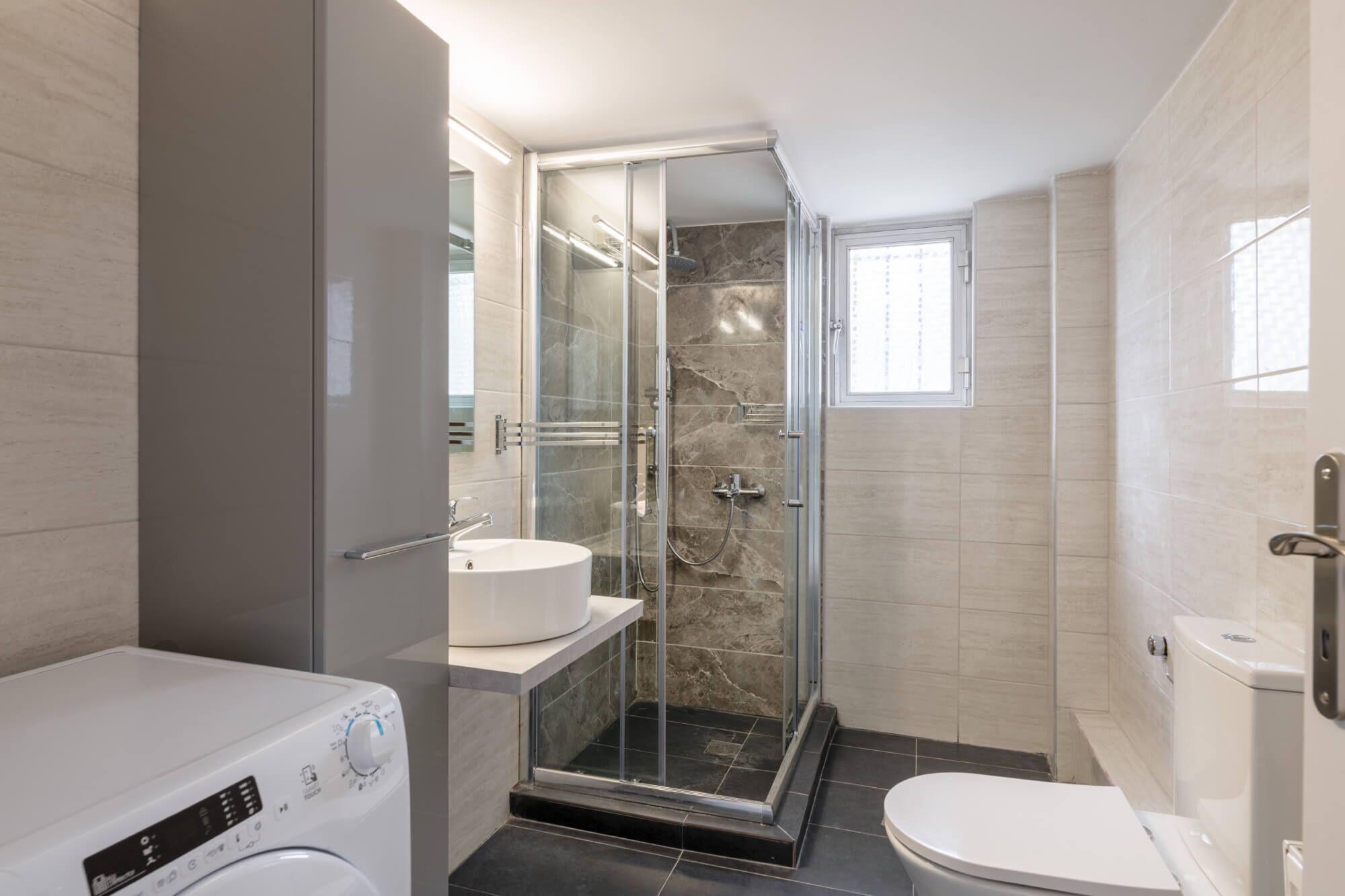 A modern bathroom with a glass-enclosed shower, a standalone sink, and a toilet.