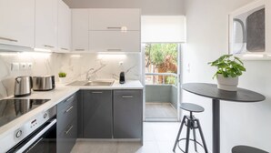 Une cuisine moderne équipée d’un four encastré, d’un évier et d’un coin repas avec une petite table et des tabourets.
