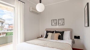 Une chambre d’hôtel avec un lit, une vue sur les bâtiments environnants et un climatiseur fixé au mur.