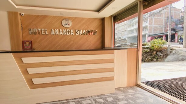 A hotel reception desk with a wooden finish and a sign that reads "HOTEL ANANDA BHARAV". - MeroStay 107 Hotel Bhairav Ananda  (Kathmandu)