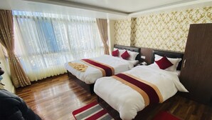 A hotel room with two beds, wooden flooring, a large window with curtains, and patterned wallpaper. - MeroStay 107 Hotel Bhairav Ananda  (Kathmandu)