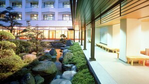 A courtyard with a koi pond, rocks, and benches. - LiVEMAX RESORT Isawa Onsen (Fuefuki)