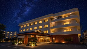 A multi-story hotel with a modern design, featuring a prominent entrance, multiple windows, and a parking lot. - LiVEMAX RESORT Isawa Onsen (Fuefuki)