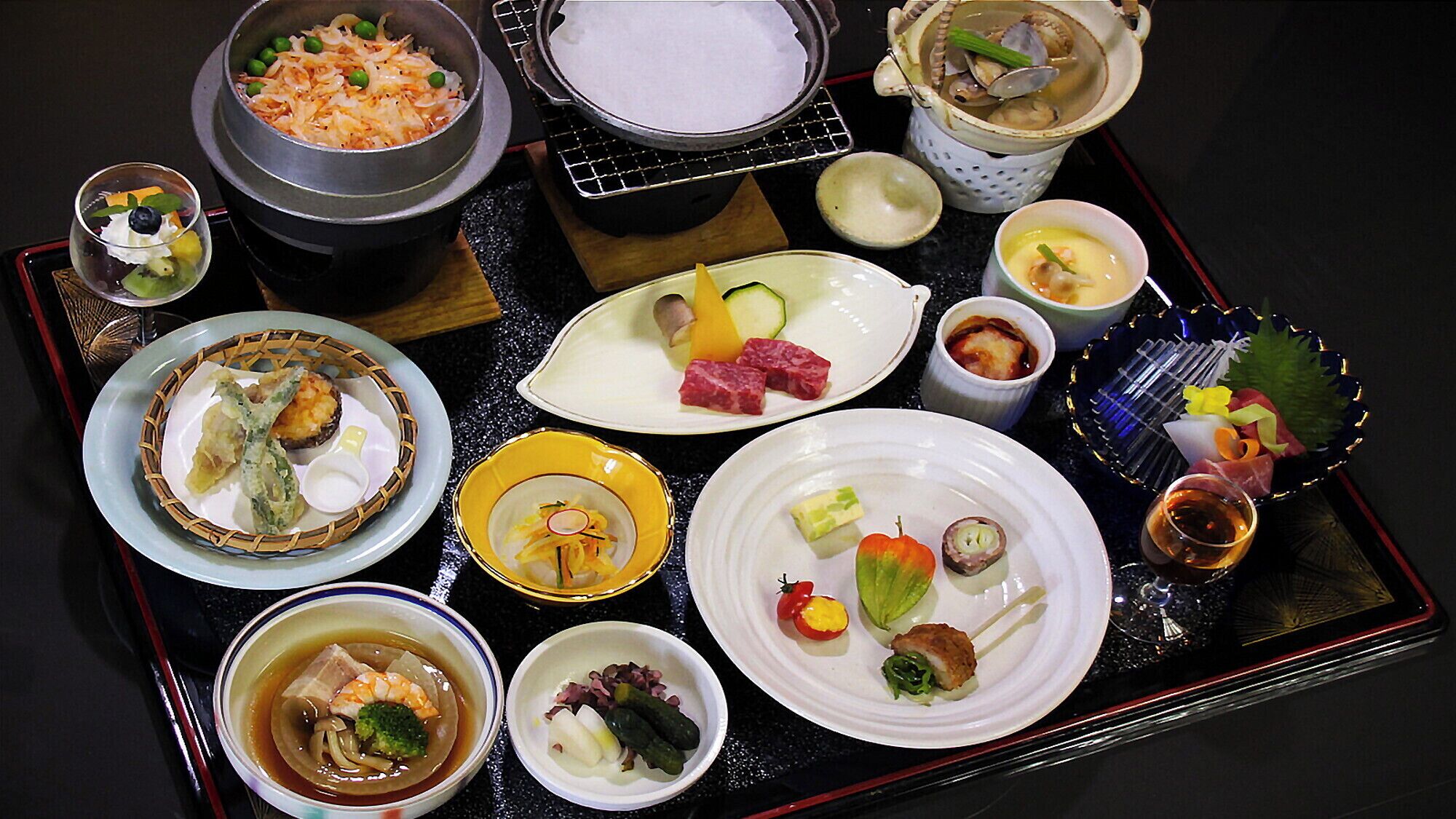Una variedad de platos en una bandeja, incluyendo sushi, sashimi y una olla de sopa.