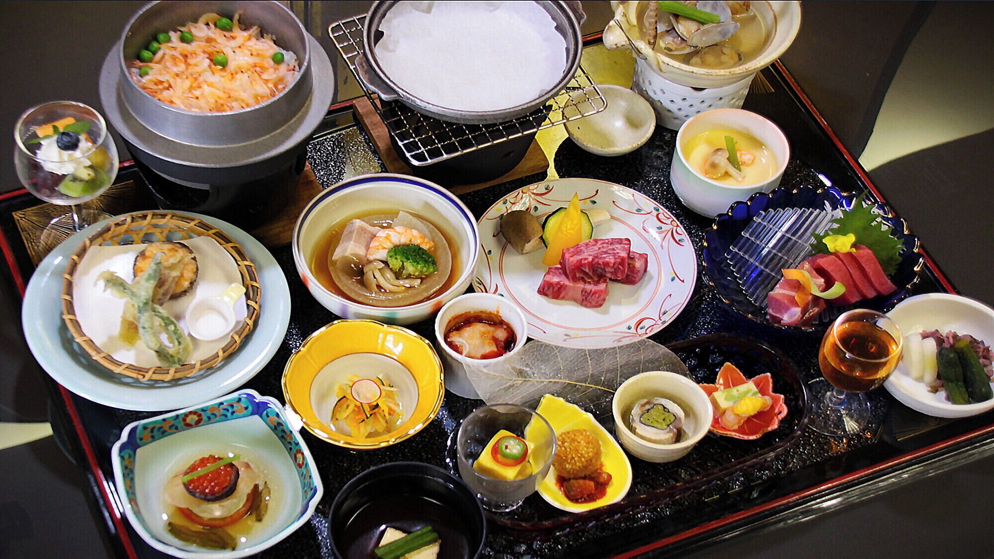 A variety of dishes on a tray, including sushi, sashimi, and other Asian cuisine.