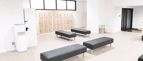 A clean, modern waiting area with benches, a trash bin, and lockers in the background.