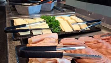 A buffet with various meats and cheeses, including sliced ham and cheese.