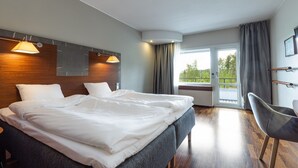 Habitación de hotel moderna con una cama grande, un escritorio y vistas al exterior.