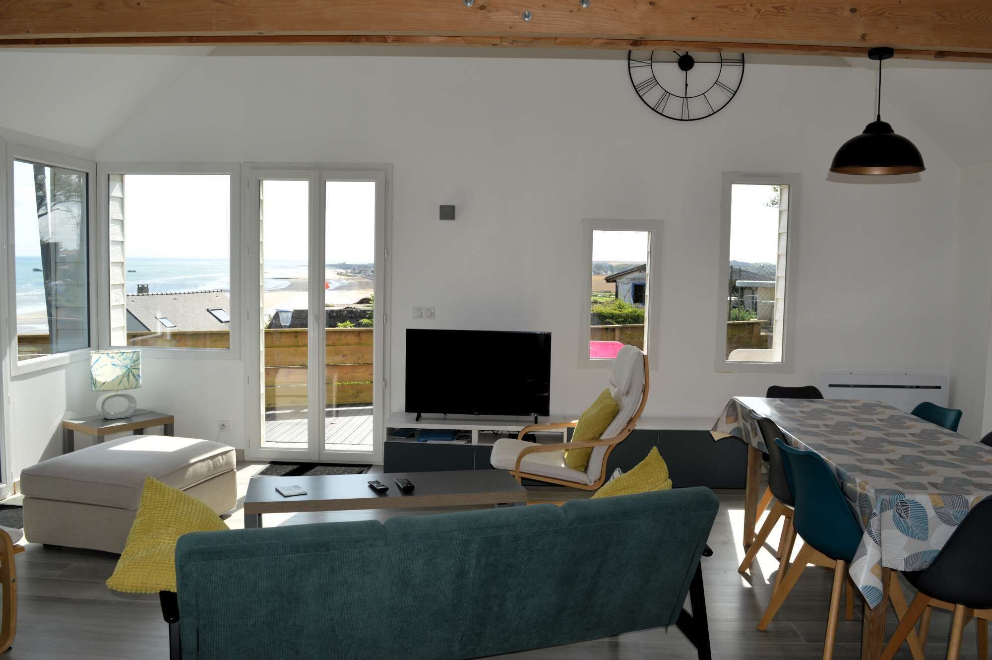 Un salón amplio con televisor grande, asientos cómodos y vista a la playa.
