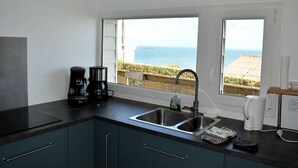 A kitchen with a view of the sea, a coffee maker, and a sink. - Le Perchoir Avec vue Mer, à 300m de la Plage (Saint-Côme-de-Fresné)