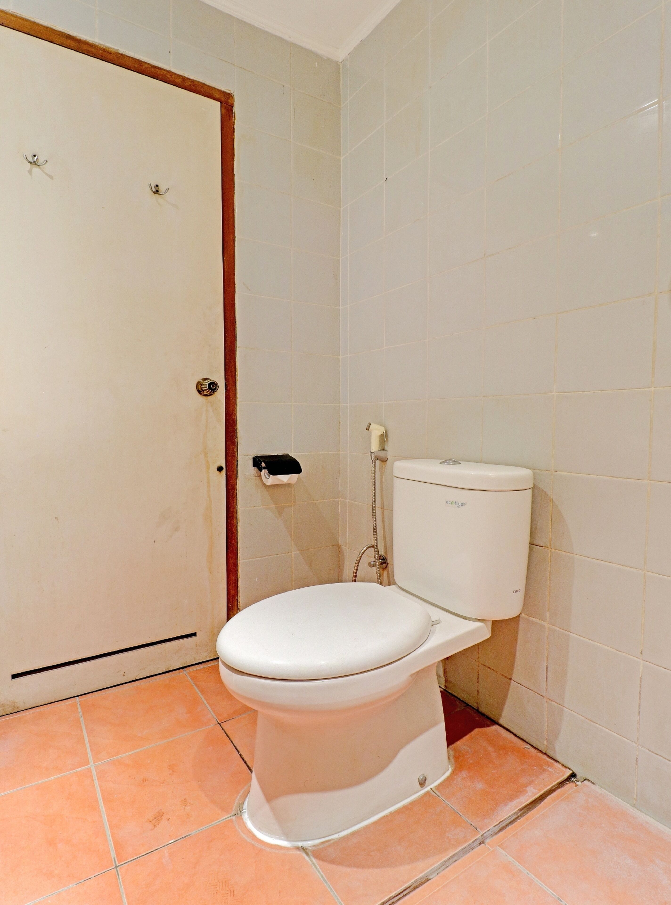 Un baño pequeño y sencillo, con inodoro, ducha y puerta.