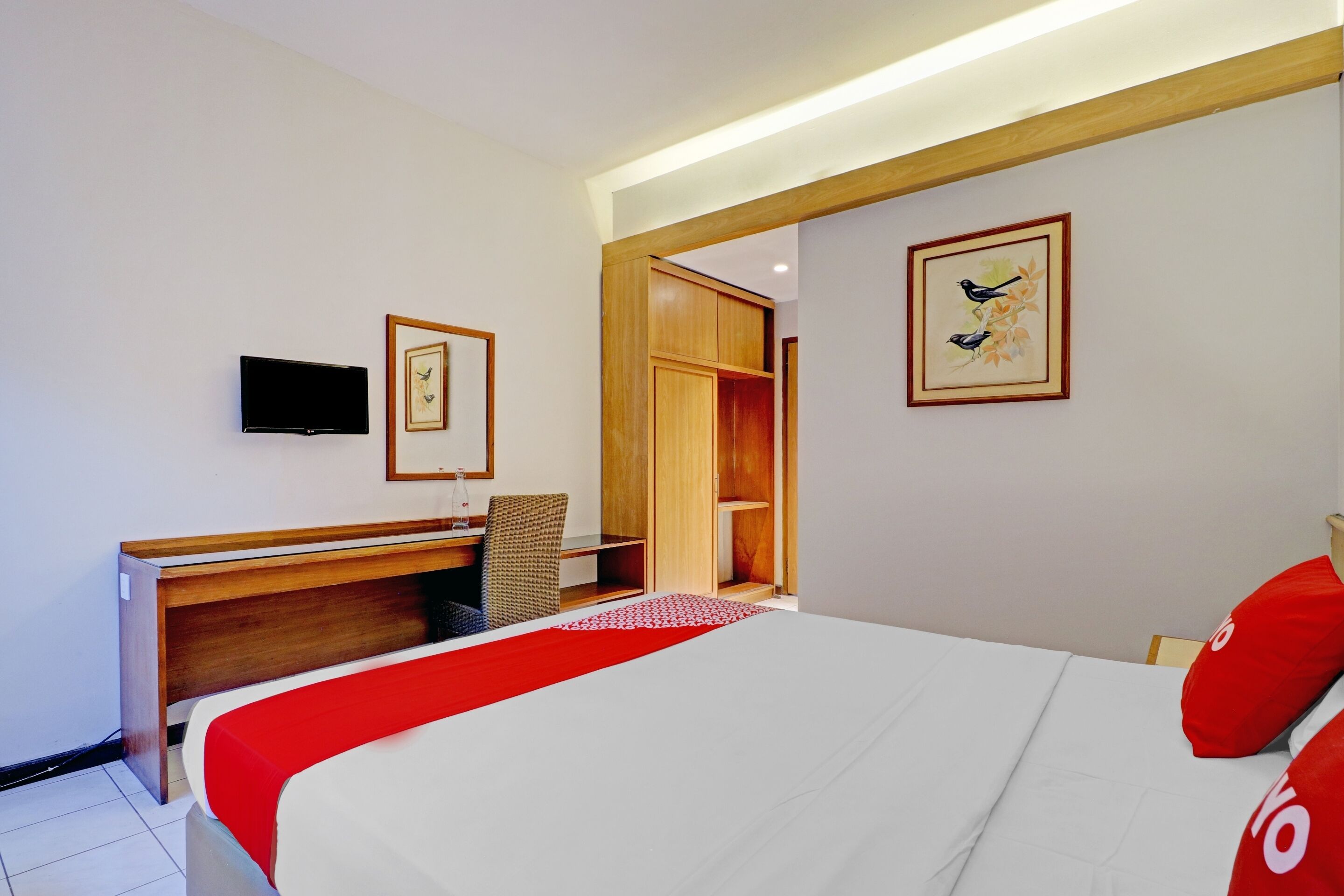 A hotel room with a bed, a desk, a chair, a TV, and a wardrobe.