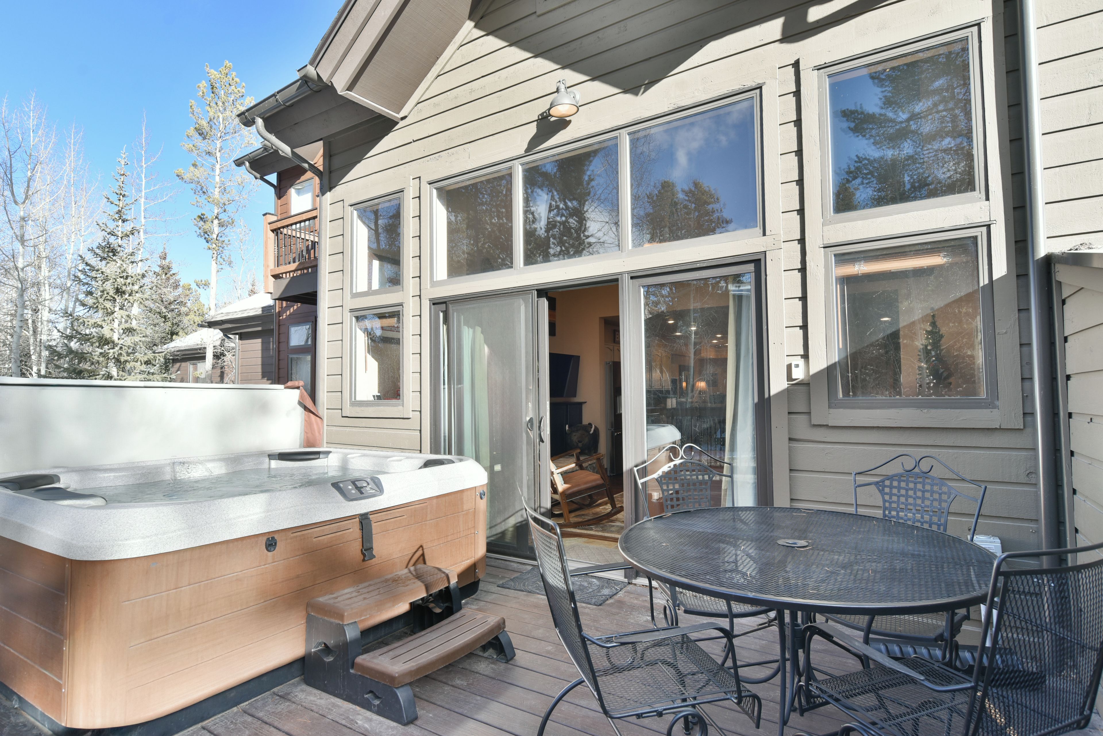 A deck with a hot tub, outdoor seating, and a large sliding glass door leading to an interior space.