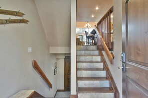 A staircase with wooden steps and a handrail, leading to a dining area with a chandelier.