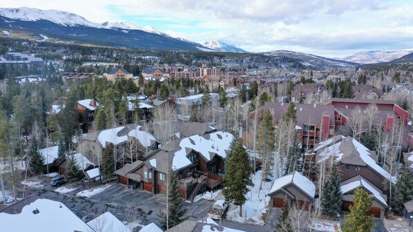 A residential area with snow-covered roofs and a mountainous backdrop.