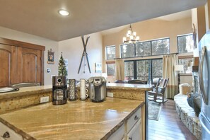A kitchen with a wooden countertop, a coffee maker, a kettle, and a Christmas tree.